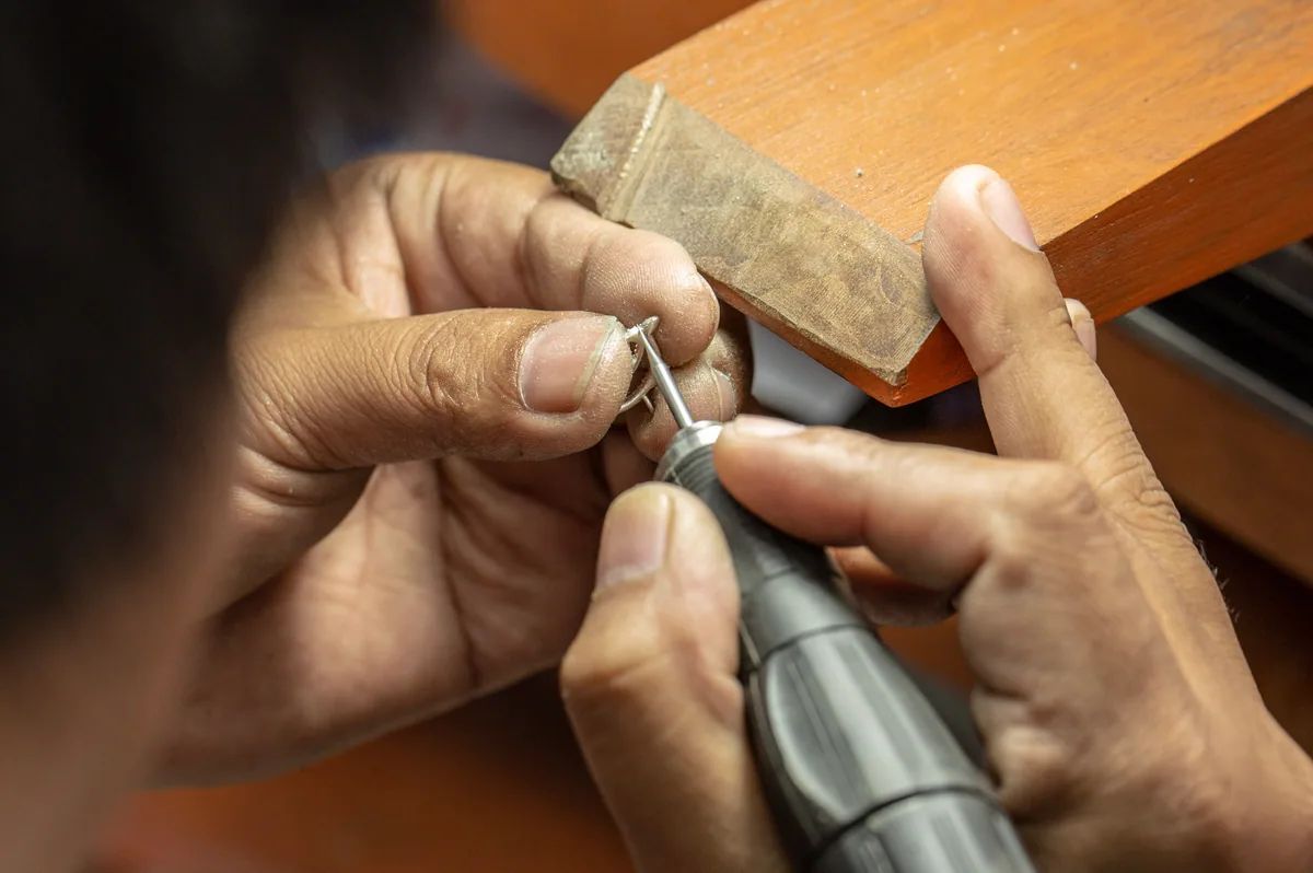 Hands finishing a gold ring with a rotary tool